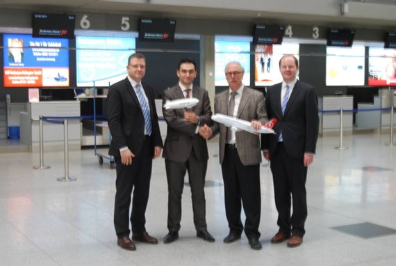 four men in suits in the airport terminal. two of the men are holding a small Turkish Airlines airplane