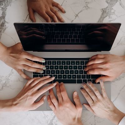 Viele Hände am Laptop