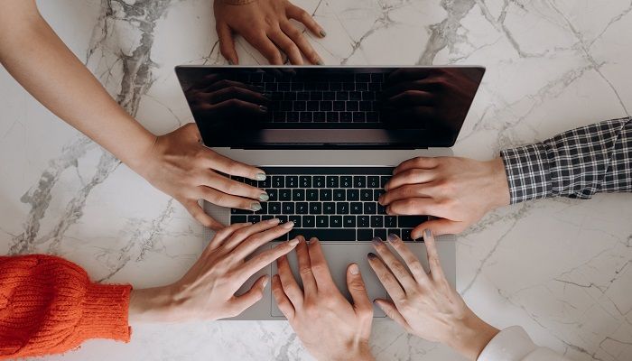 Viele Hände am Laptop