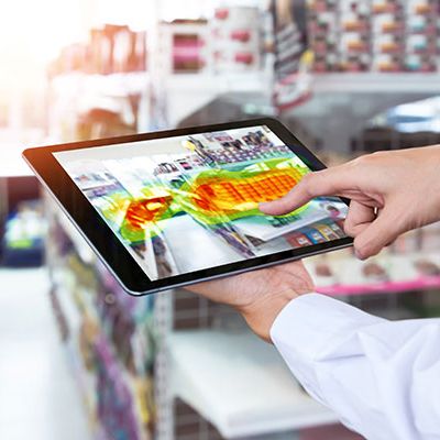 Das Bild zeigt einen Mann, der ein Tablet verwendet, um eine Heatmap Analyse zur Optimierung des Marketingmaterials für einen Supermarkt darzustellen. Diese Analyse zielt darauf ab, die Effektivität des Marketings zu steigern.