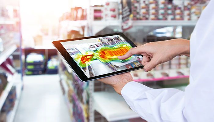 Das Bild zeigt einen Mann, der ein Tablet verwendet, um eine Heatmap Analyse zur Optimierung des Marketingmaterials für einen Supermarkt darzustellen. Diese Analyse zielt darauf ab, die Effektivität des Marketings zu steigern.
