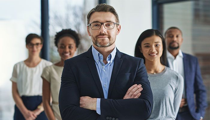Eine Führungskraft und Ihr Team stehen frontal im Büro, nachdem sie das 360-Grad-Feedback-Tool angewendet haben.