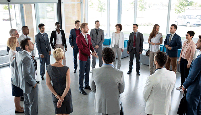 Gruppe an junger Menschen steht im Kreis und führt ein 360 Grad Feedback durch.