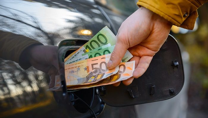 Mann steckt Geld in den Autotank