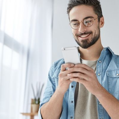 Glücklicher Mann tipp auf dem Handy