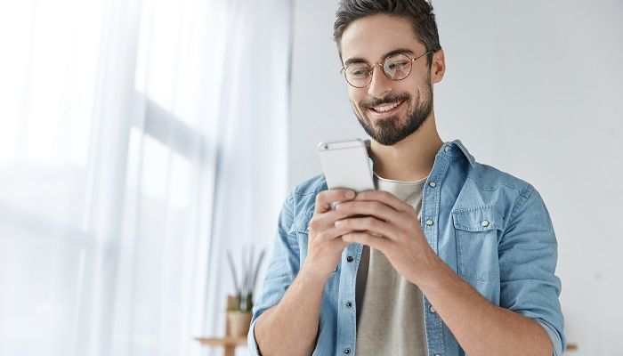 Glücklicher Mann tipp auf dem Handy