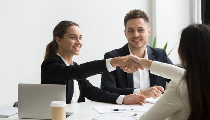 Zwei Kolleginnen schütteln sich nach positivem B2B-Kundenfeedback die Hände.