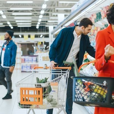 Menschen im Supermarkt suchen Lebensmittel, um anschließend B2C-Kundenfeedback abzugeben.