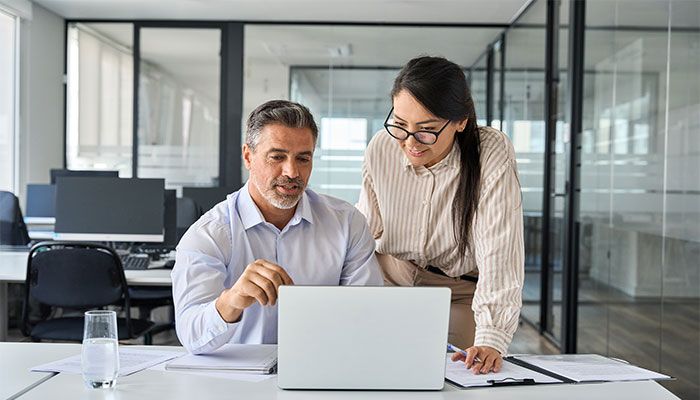 Zwei Personen diskutieren an einem Laptop über die Befragungssoftware.