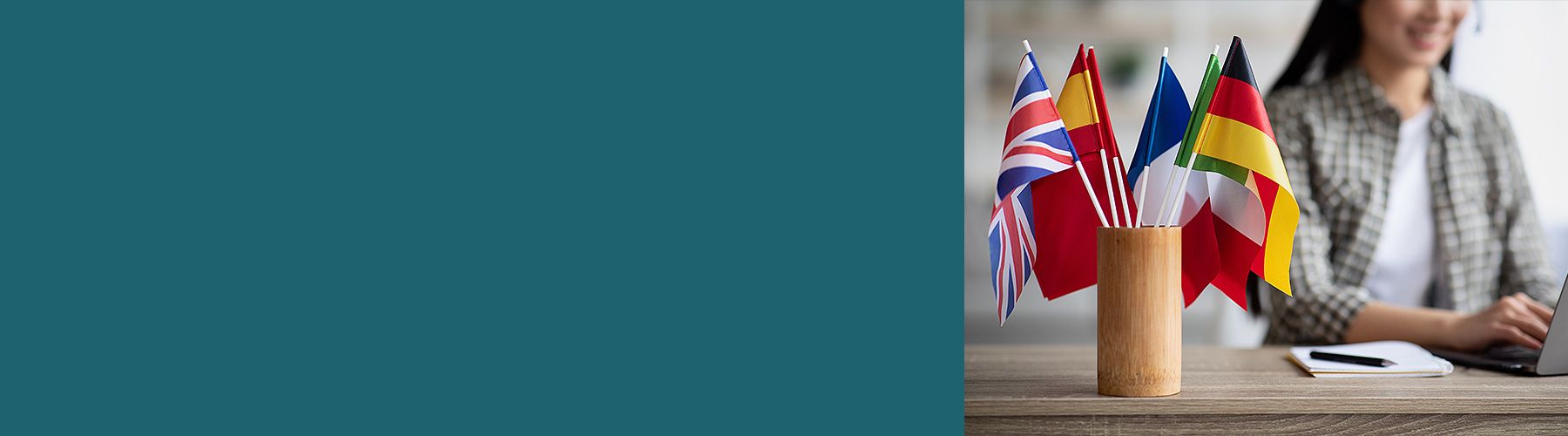 Eine Frau analysiert B2B-Kundenfeedback und vor ihr liegt auf dem Schreibtisch ein Behälter mit unterschiedlichen Länderflaggen.