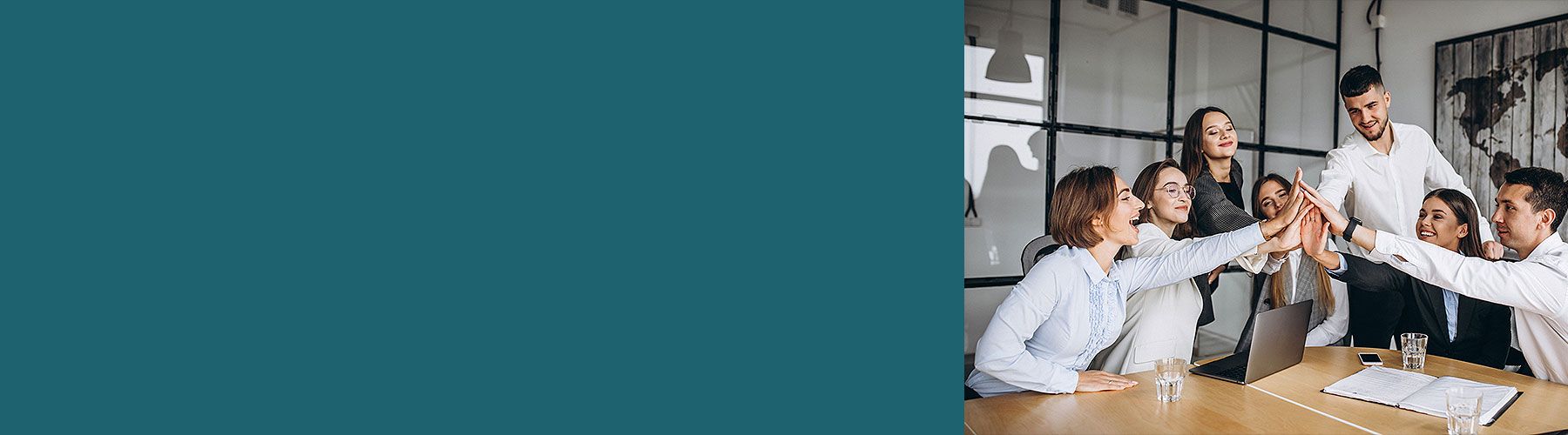 Ein junges Team sitzt zusammen und klatscht sich in der Mitte ab, weil sie eine gute Team-Führung im Unternehmen haben.