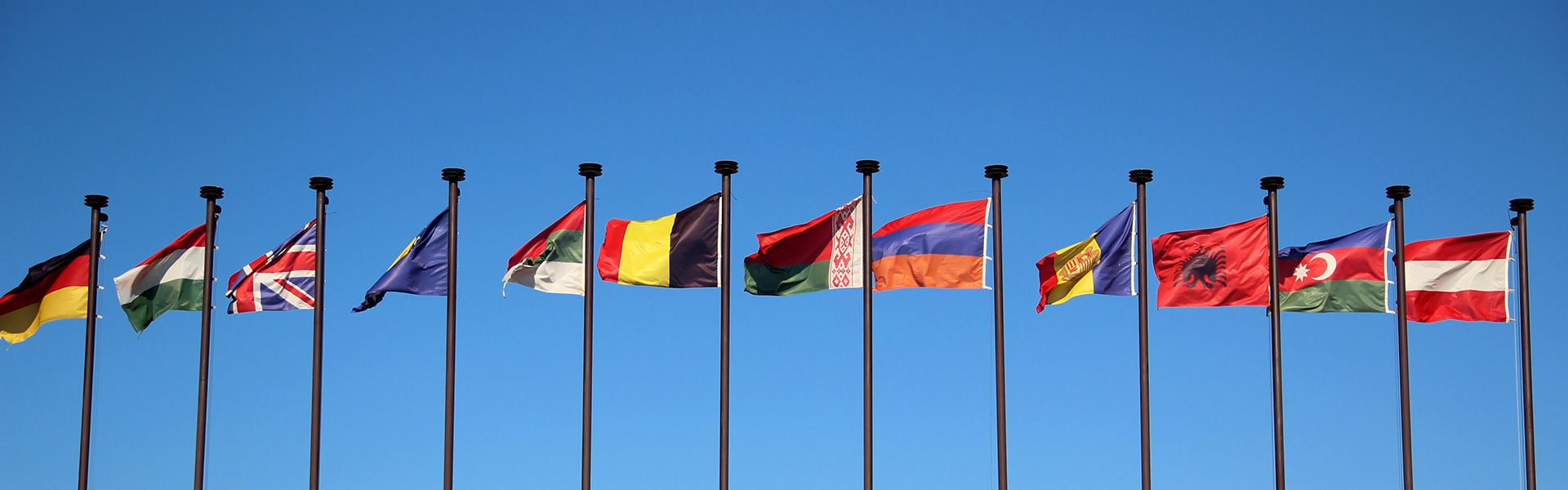 Die Vielfalt bei einer Internationale Kundenbefragung ist durch verschiedene Flaggen zu sehen, die an Masten hängen.