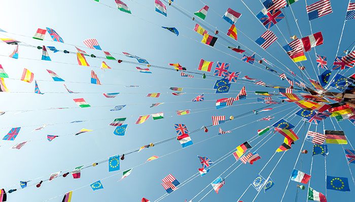 Ein Internationales Mitarbeiterfeedback wird durch Girlanden mit verschiedenen Flaggen symbolisiert.