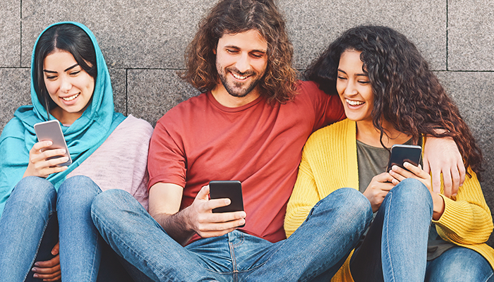 Drei junge Erwachsene führen eine Panelbefragung am Smartphone durch.