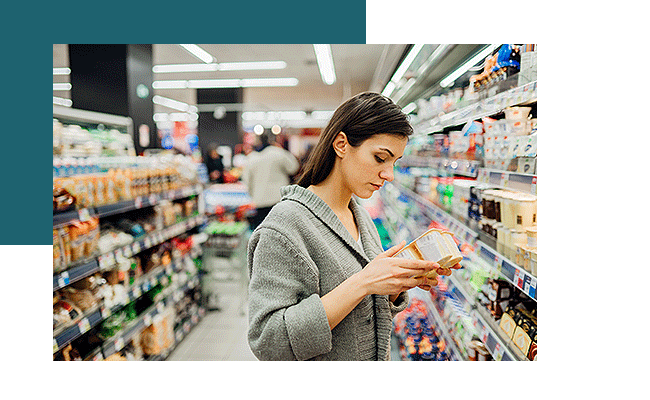 Angewandte Preisforschung: Eine Frau steht in einem Supermarkt und vergleicht Joghurts nach Preisen.
