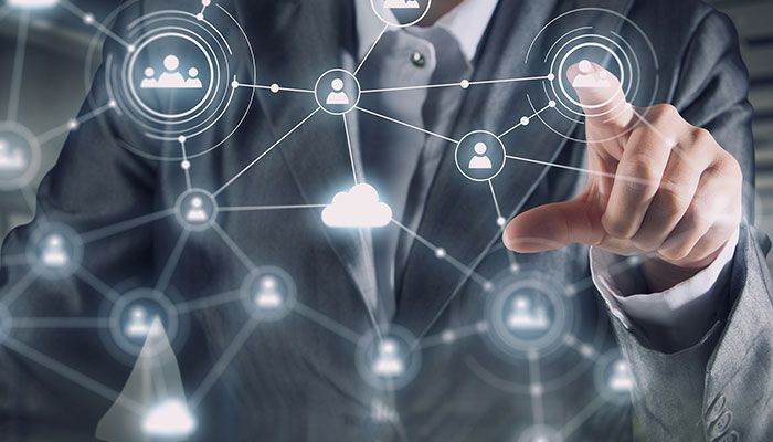 Mit Schnittstellen-Befragungen wichtige Insights gewinnen: Ein Geschäftsmann steht for einem digitalen Dashboard, auf dem ein Personen-Netz projeziert wird.