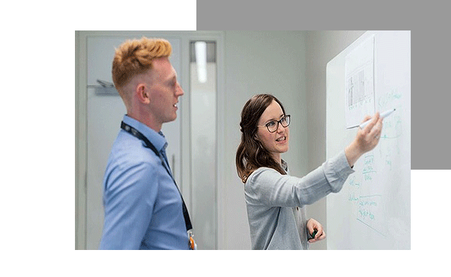 Eine Frau erklärt ihrem Kollegen am Whiteboard die Schnittstellenanbindung.