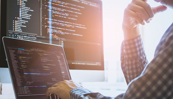 Ein Mann führt Sonderprogrammierung in einem Code-Editor an seinem Laptop