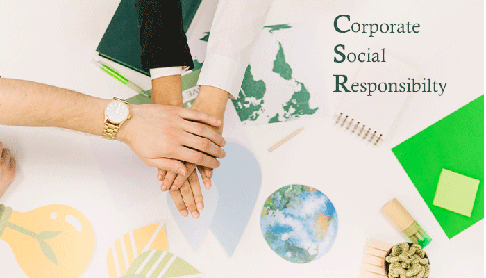 Geschäftsleute halten die Hände übereinander über einem Tisch mit Plänen zu Nachhaltigkeit undCSR