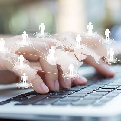 Hände beim Tippen, umgeben von einem Schatten der Weltkarte und Schatten von Menschen