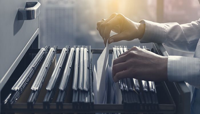 Eine Person sortiert die Akten des Mitarbeiterfeedback für Behörden.