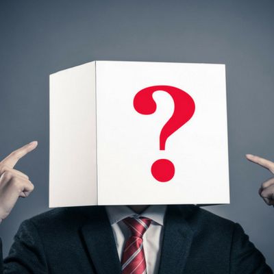 Eine Person im Anzug hat einen Karton mit einem aufgedruckten Fragezeichen auf dem Kopf welches für eine anonyme Mitarbeiterbefragung steht.