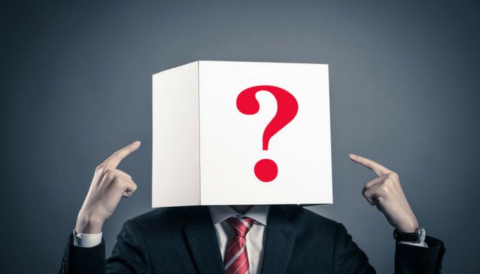 Eine Person im Anzug hat einen Karton mit einem aufgedruckten Fragezeichen auf dem Kopf welches für eine anonyme Mitarbeiterbefragung steht.