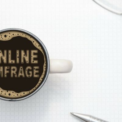 In einem Kaffebecher ist mit Kaffeeschaum Anschreiben Kundenbefragung geschrieben.