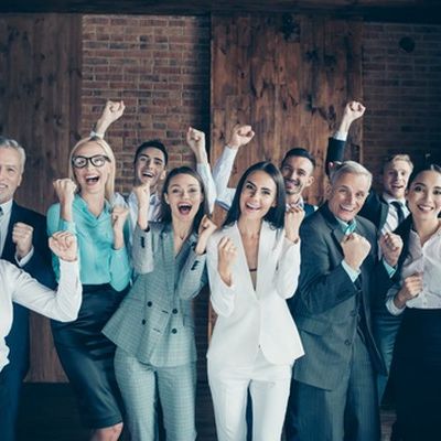 Ein unternehmerisches Team lacht in die Kamera. Das zeugt von einem guten Betriebsklima.