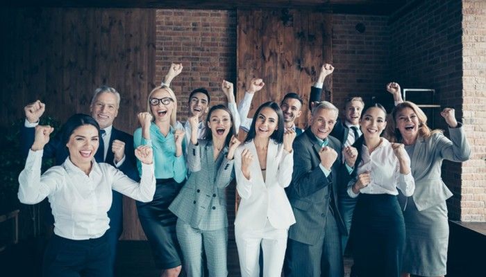 Ein unternehmerisches Team lacht in die Kamera. Das zeugt von einem guten Betriebsklima.