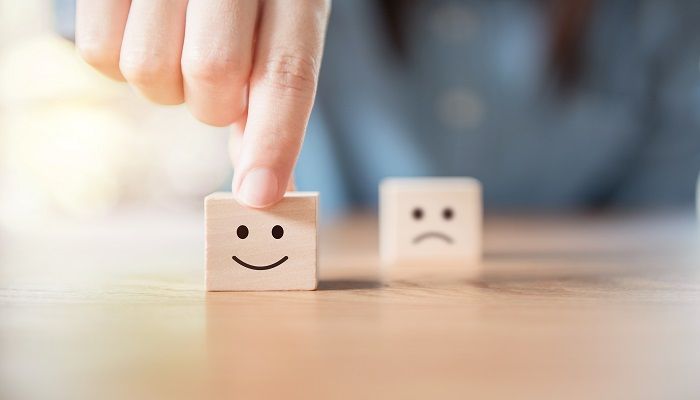 Der Customer Effort Score definiert die Zusammenarbeit mit einem Lieferanten oder Dienstleister. Ein Würfel mit einem traurigen und einem lachenden Gesicht symbolisiert die Zufriedenheit des Kunden mit der Zusammenarbeit.