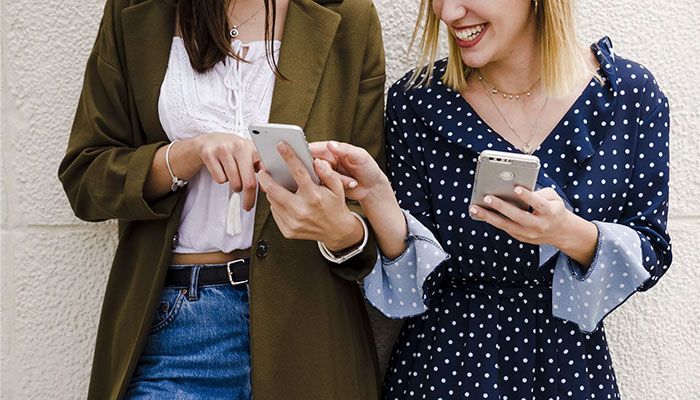 Die Vorzüge des Customer Effort Scores sind eindeutig. Freundinnen halten Handys in der Hand und zeigen sich etwas auf dem Bildschirm.