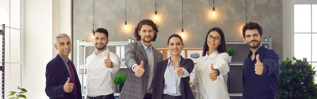 Mitarbeitende schauen lächelnd in die Kamera und zeigen mit dem Daumen nach oben. Ein Zeichen für einen hohen ENPS Wert.