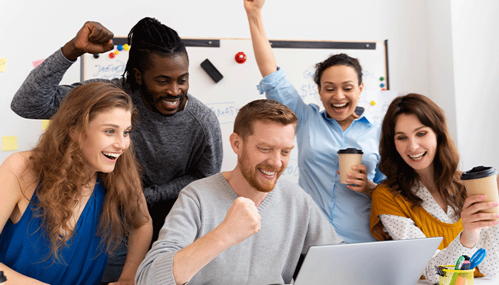 Eine Gruppe an jungen Kollegen sitzt vor einem Laptop und freut sich über einen guten ENPS Wert.