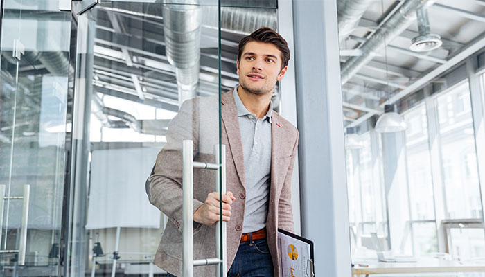 Ein Mann hält die Ergebnisse eines Exit-Interviews in der Hand und betritt ein Bürozimmer.