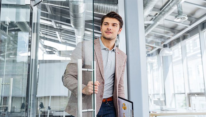 Ein Mann hält die Ergebnisse eines Exit-Interviews in der Hand und betritt ein Bürozimmer.