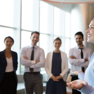 Eine junge Frau gibt ihren Kollegen und Kolleginnen ein Training zum Thema Führungskompetenz.