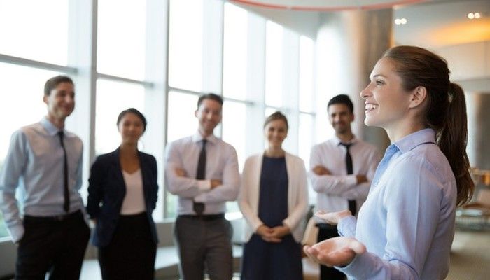 Eine junge Frau gibt ihren Kollegen und Kolleginnen ein Training zum Thema Führungskompetenz.