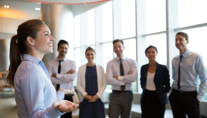 Eine junge Frau gibt ihren Kollegen und Kolleginnen ein Führungskräfte Coaching.