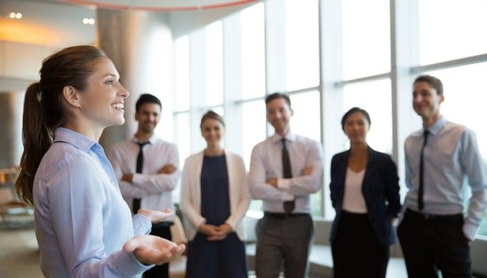 Eine junge Frau gibt ihren Kollegen und Kolleginnen ein Führungskräfte Coaching.