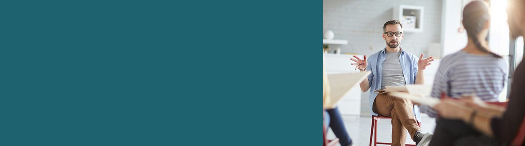 Ein Mann sitzt vor einer Gruppe und gibt ein Führungskräfte Coaching.