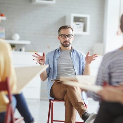 Ein Mann sitzt vor einer Gruppe und gibt ein Führungskräfte Coaching.