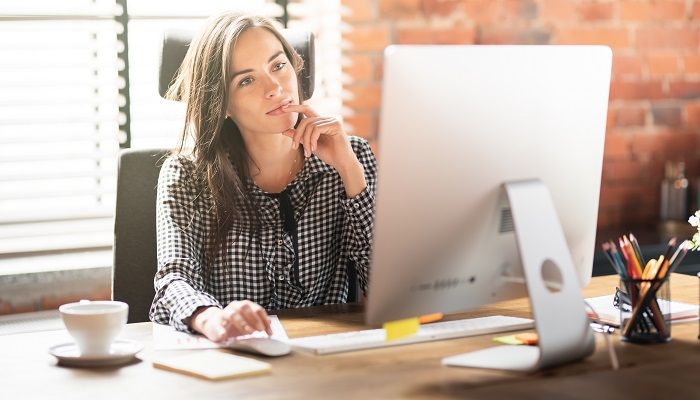 Eine Frau sitzt im Büro vor ihrem Monitor und nimmt an einem Führungskräfte Coaching teil.