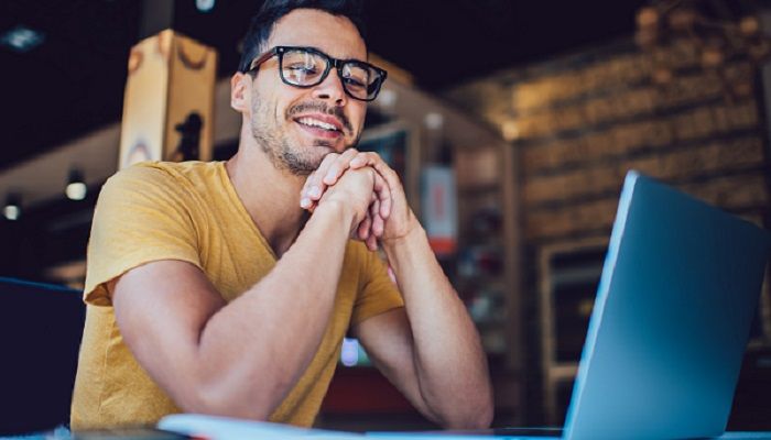 Ein zufriedener Programmierer schaut auf seinen Laptop und erhält Führungskräftefeedback.