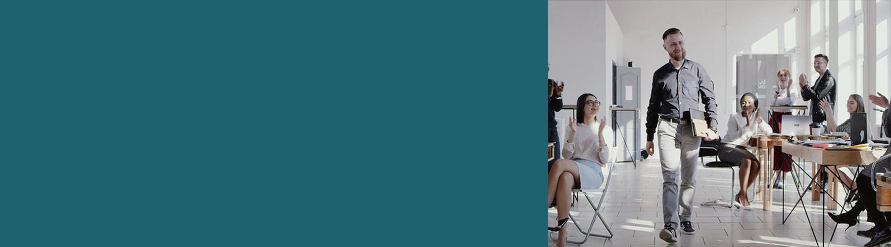 Einen einem positiven Führungxskräftefeedback läuft ein Mann mit Unterlagen zufrieden durch das Büro und wird dabei von seinen Kollegen und Kolleginnen positiv empfangen.