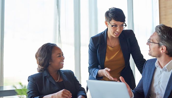 Eine Geschäftsfrau erklärt ihrer Kollegin und ihrem Kollegen, wie man eine Gefährdungsbeurteilung durchführen kann.