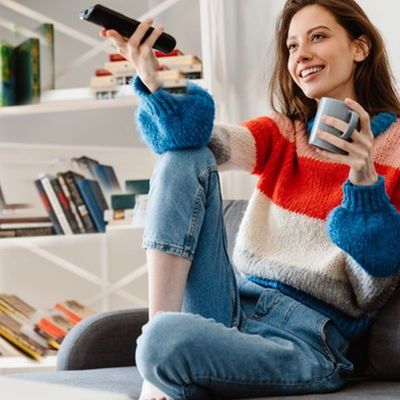 Junge Frau nimmt auf dem Sofa an einer HbbTV-Befragung teil.