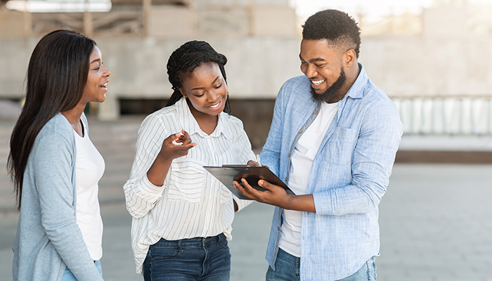 Ein Mann führt eine Konsumentenbefragung mit zwei Frauen durch und alle Beteiligten lächeln.