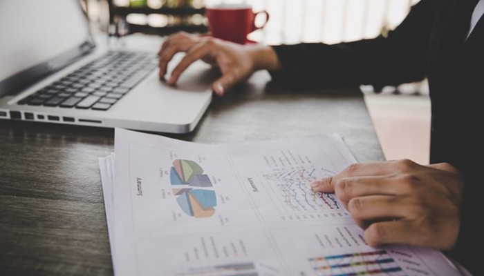 Eine Person sitzt am Laptop und analysiert Datensätze einer Konsumentenbefragung.