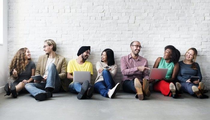 Eine Gruppe an Menschen sitzt auf dem Boden und nimmt an unterschiedlichen Geräten an einer Konsumentenbefragung.